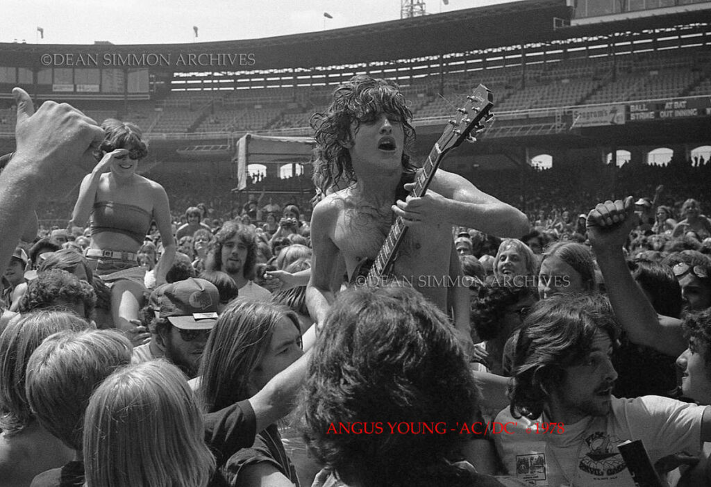 ANGUS YOUNG, LEADER OF 'AC/DC', ROCKS THROUGH THE CROWD ON BON SCOTTS SHOULDERS IN CHICAGO AT COMISKEY PARK DURING THEIR "POWERAGE" TOUR IN 1978.